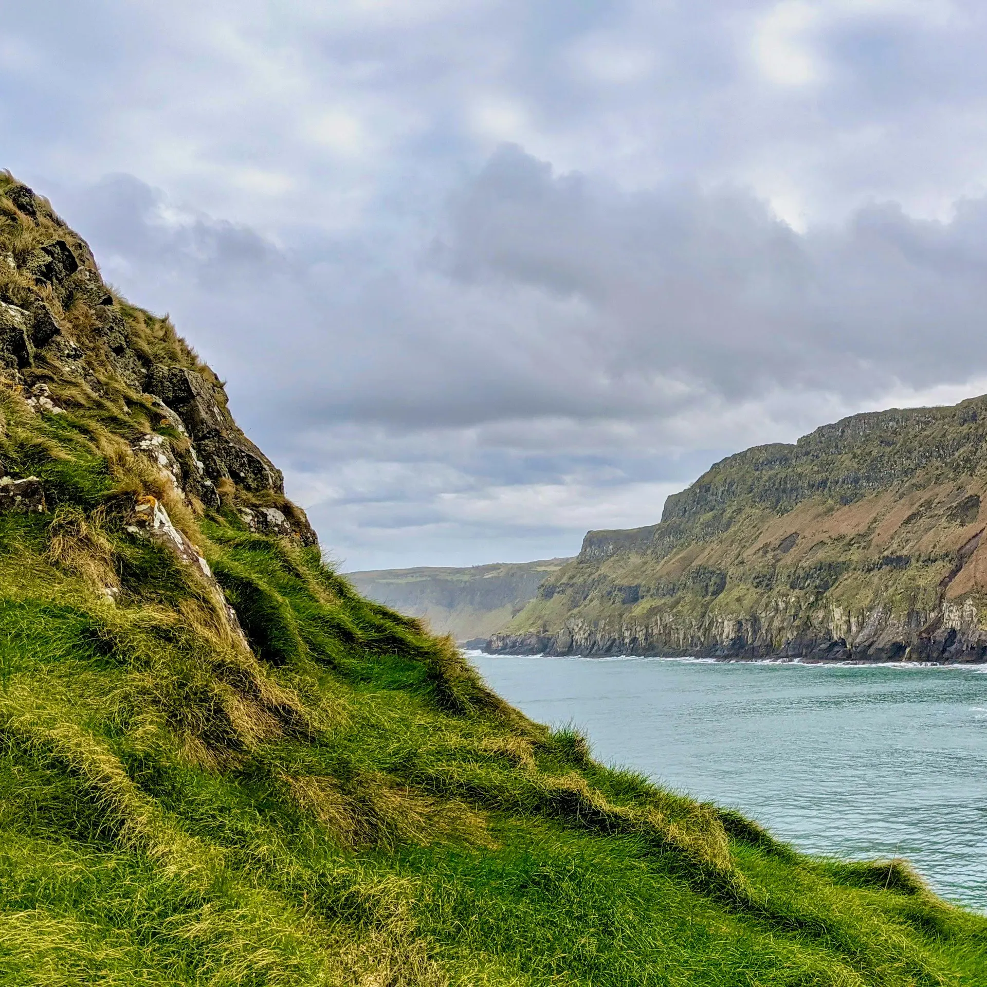 Walkers on a green Irish ridge under soft cloud